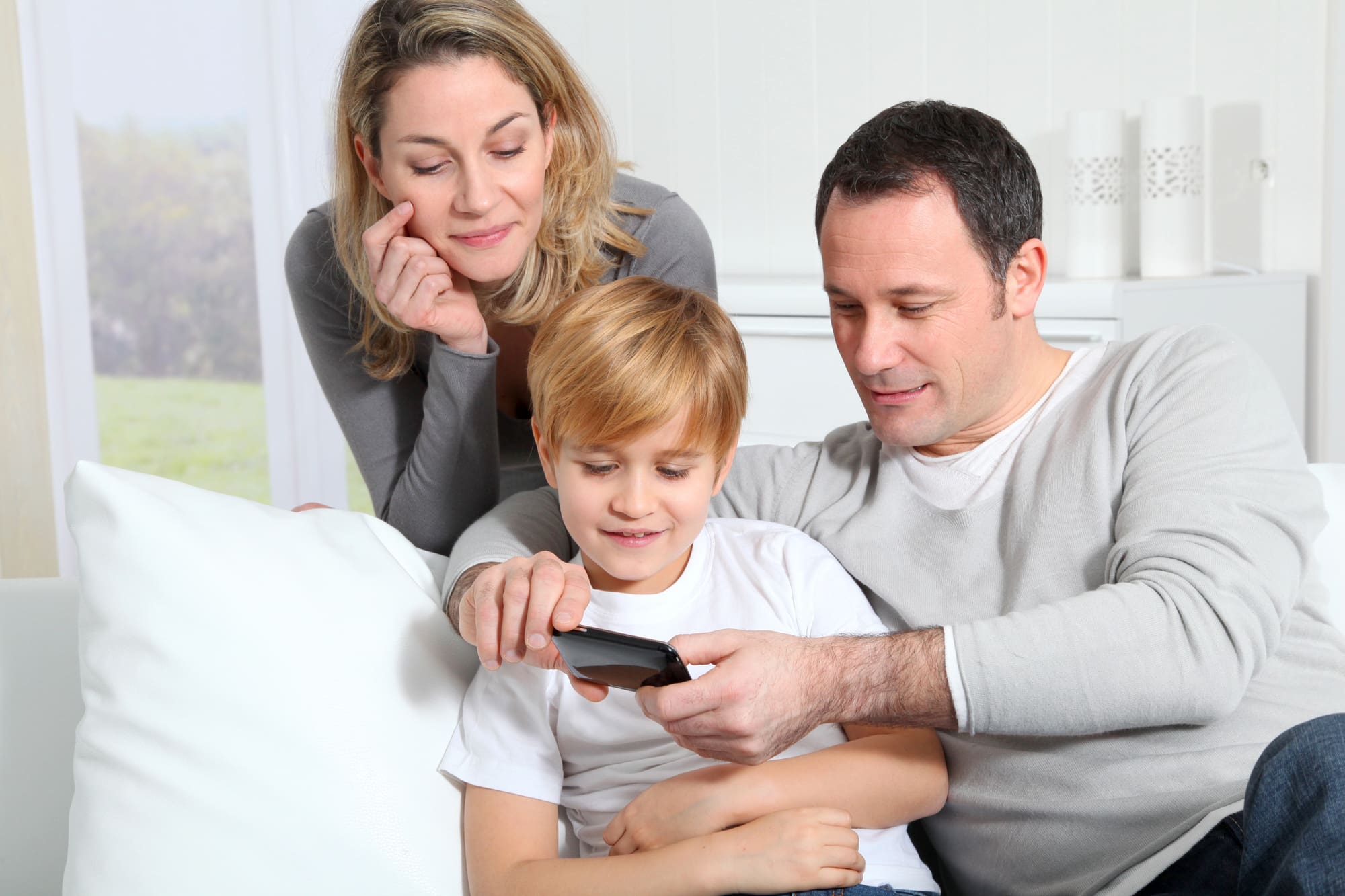 Family exploring smart home installation Cleveland options on smartphone in their bright living room.