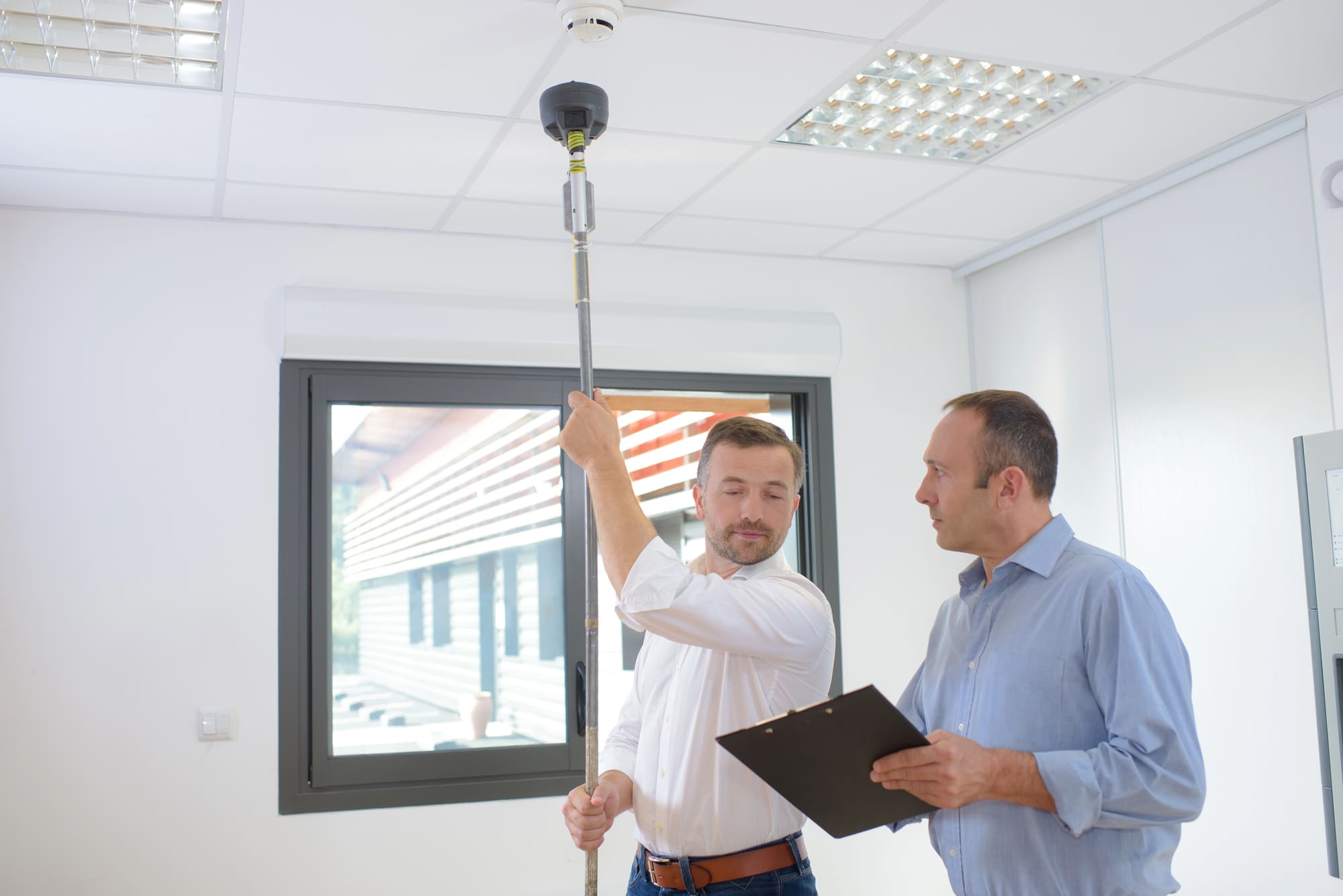 commercial fire alarms testing Commercial fire alarms technician testing smoke detector in office building