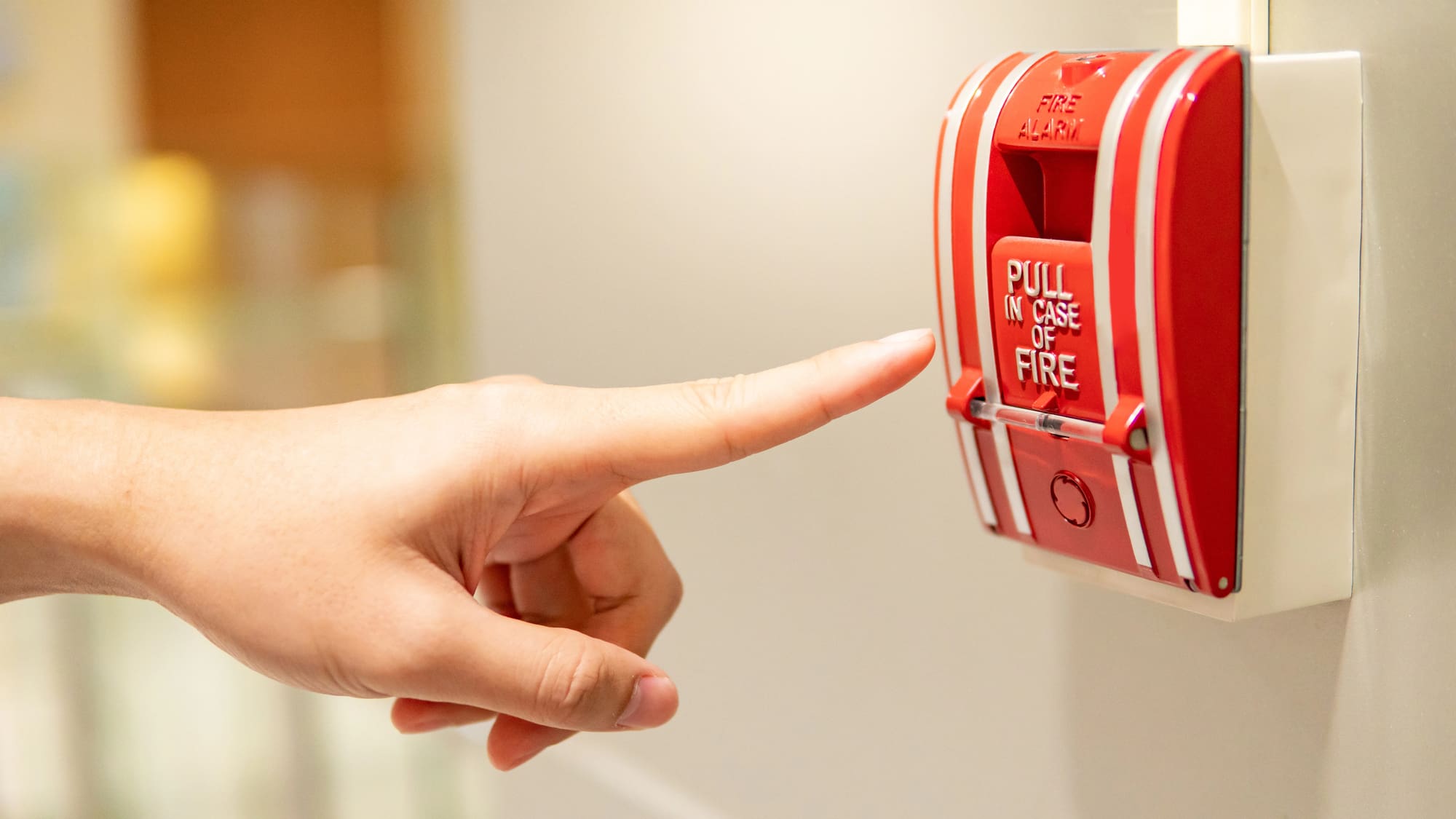 Commercial fire alarm installation Cleveland with hand reaching for red pull station