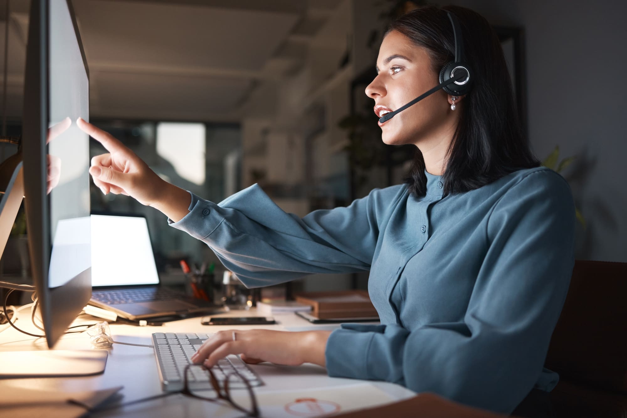 Commercial fire alarm monitoring services specialist reviewing alert on computer with headset on